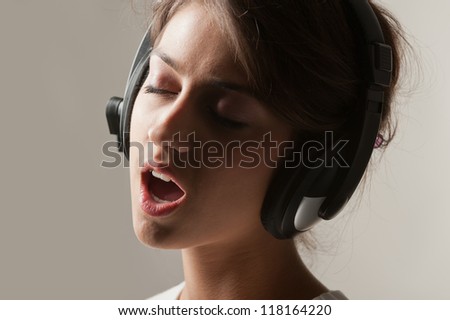 Photo in profile expressive girl in headphones singing emotionally
