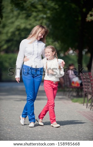 Mother and daughter walking in the summer park