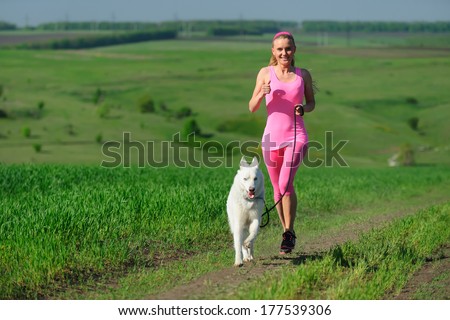 Woman runner running with dog on country road in summer nature, fitness and exercising outdoors, motion blur. Cross country running with friend.