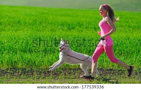 Woman runner running with dog on country road in summer nature, fitness and exercising outdoors, motion blur. Cross country running with friend.