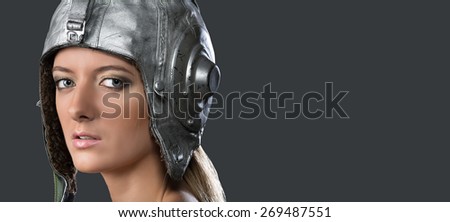 Portrait of a young girl in a leather helmet pilot on a gray background. Studio, close-up