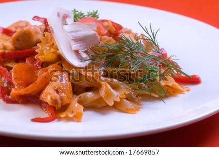 Freshly cooked plate of macaroni with chamignons and tomatoes sprinkled with fresh green herbs.