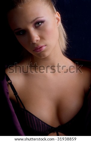 portrait of a young beautiful girl in their underwear and lilac jacket on a black background
