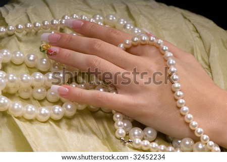 close-up female hand with a French manicure on a background of bright fabric and pearl