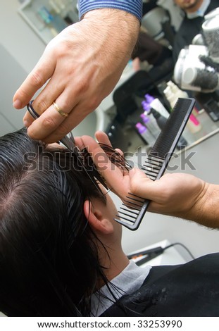 man trim young man with the help of scissors and comb
