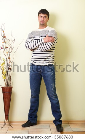 young men in dark blue jeans and sweater with stripes on a light background