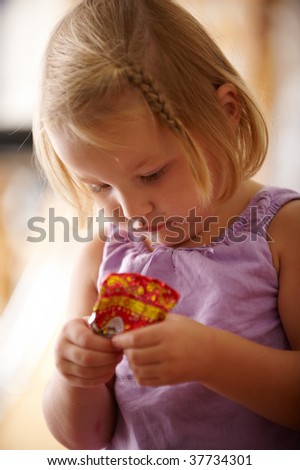 little girl in a purple dress standing with wrappers from the candy in the hands