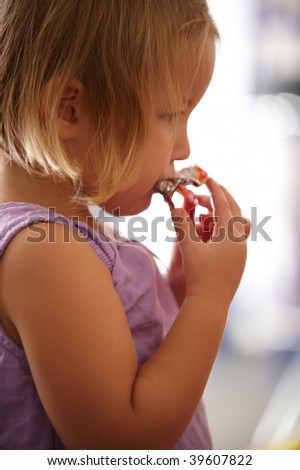 little girl in a purple dress and is eating candy