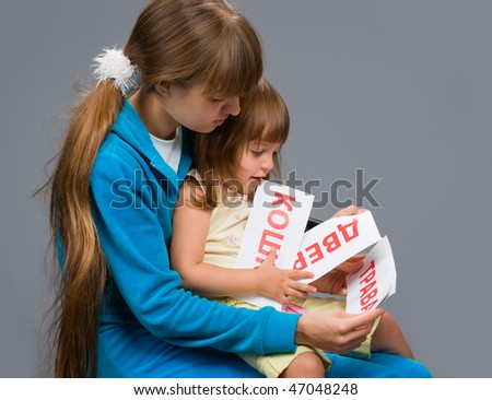 a young girl in a blue suit sitting with a child in her arms and teaches her to read