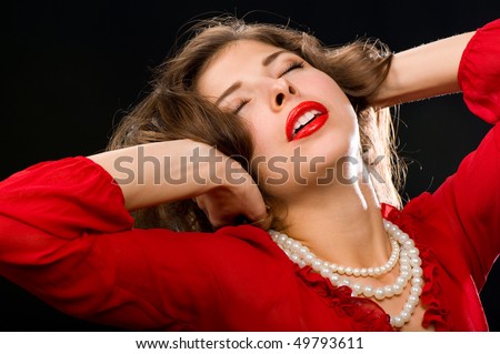 an attractive brunette in a red blouse and red lipstick on her lips, with a pearl necklace around his neck