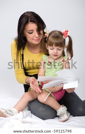 young and beautiful mother and daughter sitting on the floor and learn to read