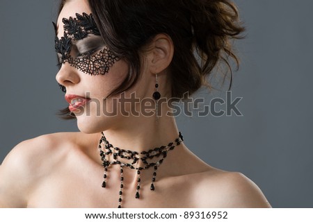 Portrait in profile of sensual girls in lace mask and bare shoulders posing in studio