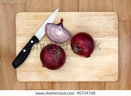 Red onions and knife on chopping board