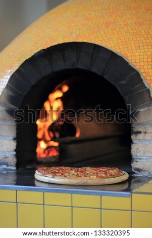 fresh pizza in traditional oven with wood fire