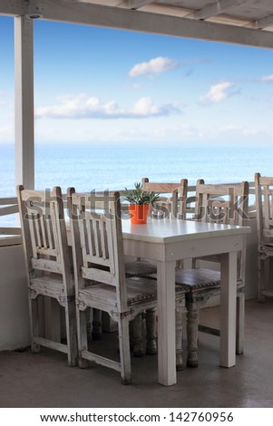 orange vase with flower on a table of a restaurant with sea view