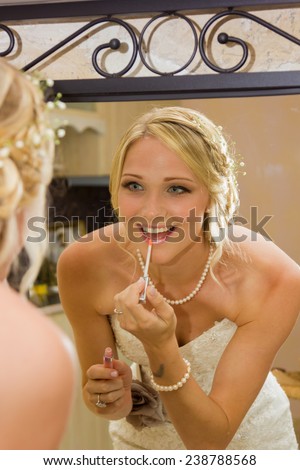 bride looking at the mirror and she is putting a lip gloss