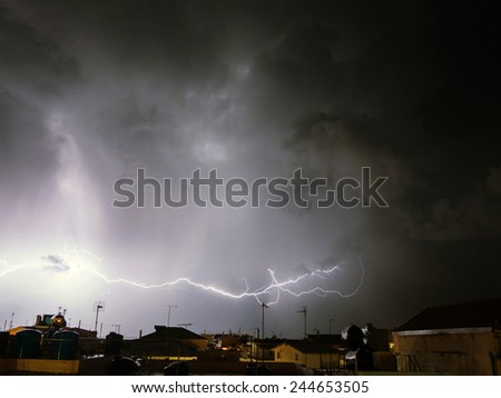 big strike in the sky with storm above a city