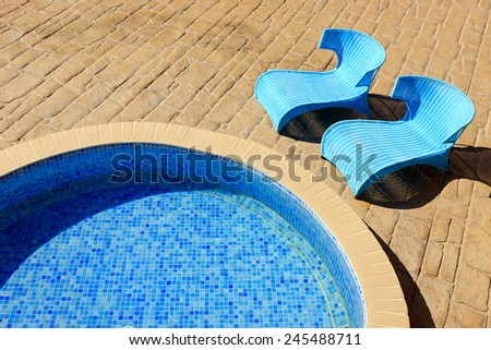 closeup of a small pool with blue stylish sunbeds
