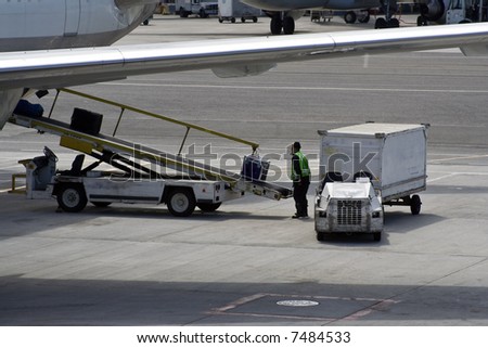 Personnel loading luggage into a plane in an airport
