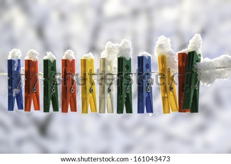 Washing line with a row of colorful pegs covered with snow queued in a row