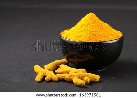 Turmeric powder in  bowl with turmeric sticks