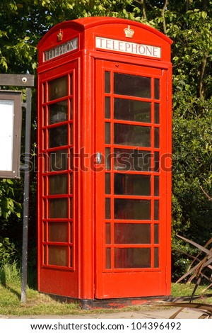 Traditional Red phone booth next to the village notice board in a typical English village