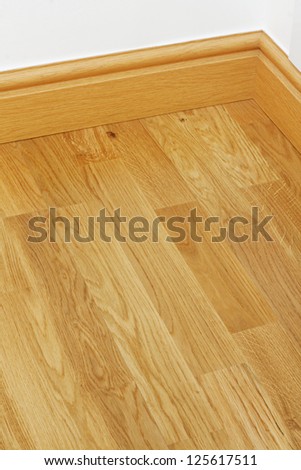 Close up showing some wood effect vinyl flooring and mdf imitation pine skirting boards in new build house