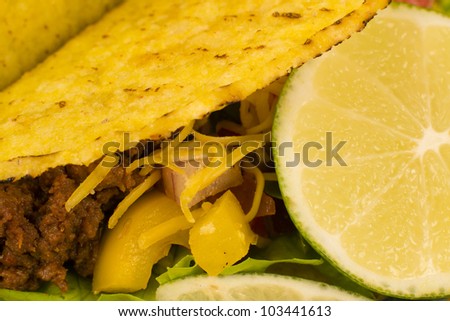Beef Tacos - Mexican minced beef hard-shell tacos with salsa, cheese and lime. Close up.