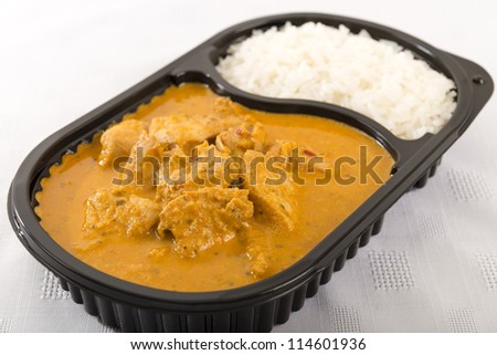 Takeaway Curry - Chicken curry with coconut milk and plain rice in a plastic container on a white background.