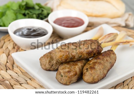 Nem Nuong Xa - Vietnamese minced pork sausages on lemongrass skewers served with chili sauce, hoisin sauce herbs and crusty baguette.