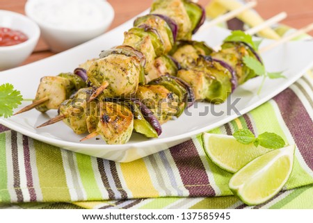 Lime, Mint & Coriander Chicken Kebabs - Marinated chicken with red onion and green peppers on skewers. Served with lime wedges, chili sauce and cucumber and yoghurt dip.