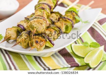 Lime, Mint & Coriander Chicken Kebabs - Marinated chicken with red onion and green peppers on skewers. Served with lime wedges, chili sauce and cucumber and yoghurt dip.