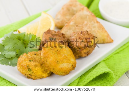 South Asian Starter Selection - Aloo Tikki, Onion Bhaji and Vegetable Samosas, served with lemon wedges, salad and dipping sauce.