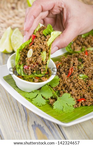 Larb - Lao minced beef salad with fish sauce, lime juice, roasted ground rice and fresh herbs served with lettuce leaves for wraps.