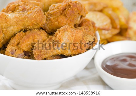 Fried Hot Chicken Wings - Chicken wings dusted in spicy flour and fried until crispy. Served with bbq sauce and potato wedges.