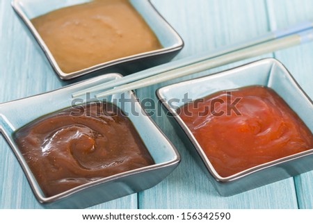 Asian Style Dips - Hoisin sauce, soybean paste and chili sauce on a blue background.