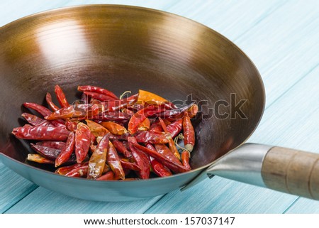 Red Dried Chillies - Dry chillies in a wok on a blue background.