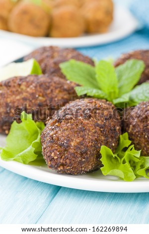 Kibbeh - Middle Eastern minced meat and bulghur wheat fried snack. Also popular party dish in Brazil (kibe). Falafel on background.