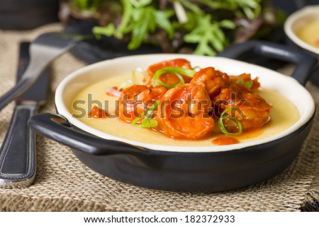 Spicy Prawns & Polenta - Soft polenta with goat\'s cheese topped with prawns in tomato and chili sauce garnished with spring onion. Served with salad.