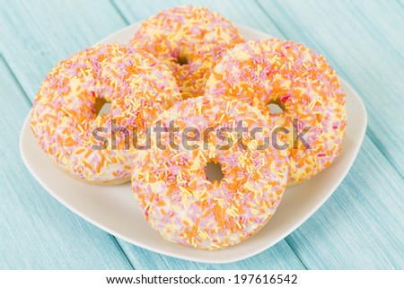 Doughnuts - Ring doughnuts topped with cake frosting and colorful sprinkles on a blue background.