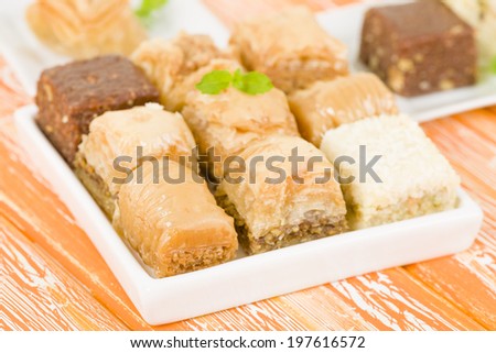 Baklava - Middle Eastern sweet pastry and nuts selection on an orange background.