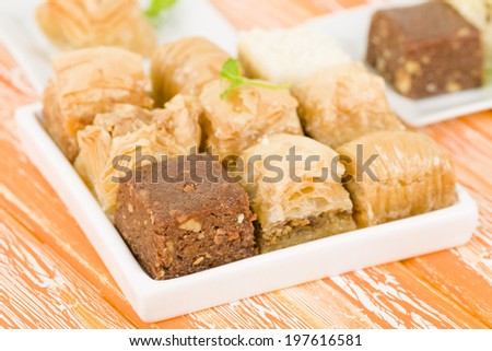 Baklava - Middle Eastern sweet pastry and nuts selection on an orange background.