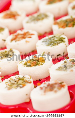 Cheese Appetisers - Soft cheese topped with herbs, spices and vegetables served on a red tray.