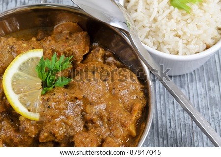 Curry & Rice - Indian curry garnished with lemon with rice on slate.