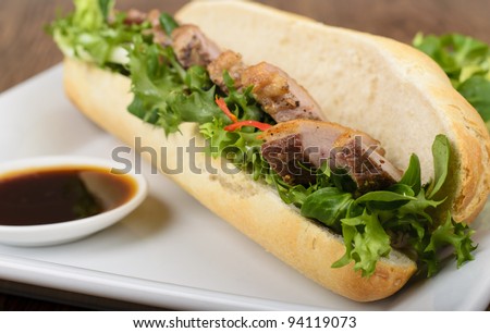 Banh mi - Vietnamese tea smoked duck sandwich with salad and dipping sauce.