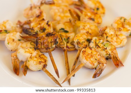BBQ Prawns - Grilled prawn skewers on a white plate /  background. Selective focus and shallow DOF.