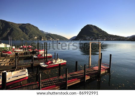 View of Lugano pier in front of Monte San Salvatore. Rent boat