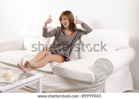 Young woman thumbs up on the sofa