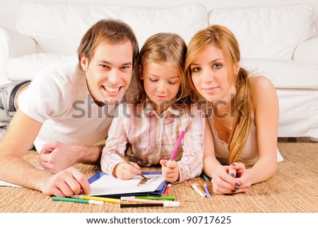Mother, father and daughter having fun at home. Doing homeworks and drawings