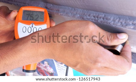 Men hand held the dry film thickness gauge to check the coating thickness.